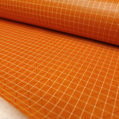 High-quality image showcasing my Carrot Orange 210D UHMWPE Gridstop Nylon fabric, emphasizing its lightweight, durable woven texture and unique waterproof properties. The image highlights the fabric's intricate UHMWPE fiber grid, its robust 210D denier thickness, and the dual protective coating – 1000mm PU on the back and DWR on the front. Ideal for visualizing the fabric's application in making resilient, weather-resistant outdoor gear like backpacks, fanny packs, and reinforcement areas.