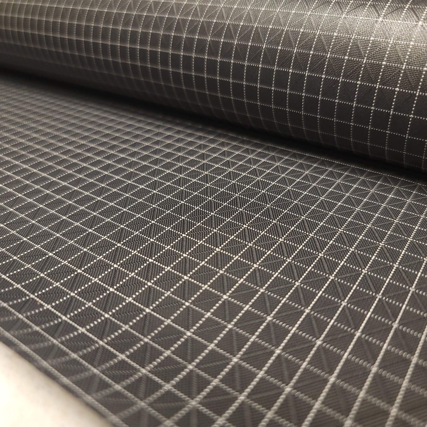 High-quality image showcasing my Charcoal Grey 210D UHMWPE Gridstop Nylon fabric, emphasizing its lightweight, durable woven texture and unique waterproof properties. The image highlights the fabric's intricate UHMWPE fiber grid, its robust 210D denier thickness, and the dual protective coating – 1000mm PU on the back and DWR on the front. Ideal for visualizing the fabric's application in making resilient, weather-resistant outdoor gear like backpacks, fanny packs, and reinforcement areas.