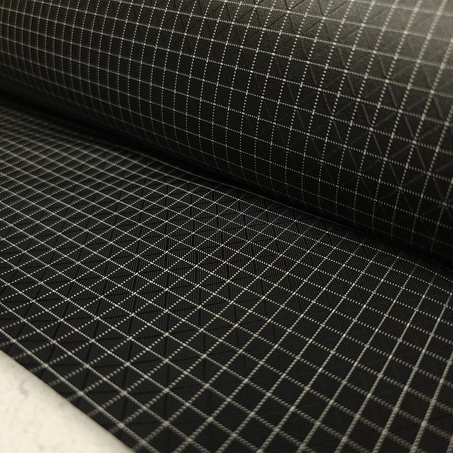 High-quality image showcasing my Eerie Black 210D UHMWPE Gridstop Nylon fabric, emphasizing its lightweight, durable woven texture and unique waterproof properties. The image highlights the fabric's intricate UHMWPE fiber grid, its robust 210D denier thickness, and the dual protective coating – 1000mm PU on the back and DWR on the front. Ideal for visualizing the fabric's application in making resilient, weather-resistant outdoor gear like backpacks, fanny packs, and reinforcement areas.