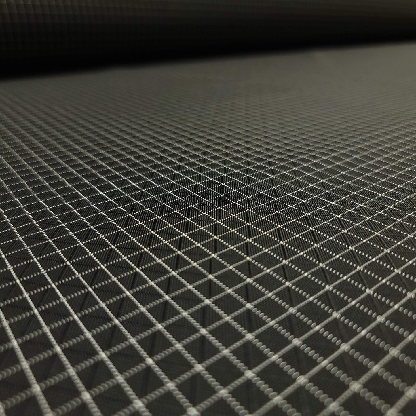 High-quality image showcasing my Eerie Black 210D UHMWPE Gridstop Nylon fabric, emphasizing its lightweight, durable woven texture and unique waterproof properties. The image highlights the fabric's intricate UHMWPE fiber grid, its robust 210D denier thickness, and the dual protective coating – 1000mm PU on the back and DWR on the front. Ideal for visualizing the fabric's application in making resilient, weather-resistant outdoor gear like backpacks, fanny packs, and reinforcement areas.