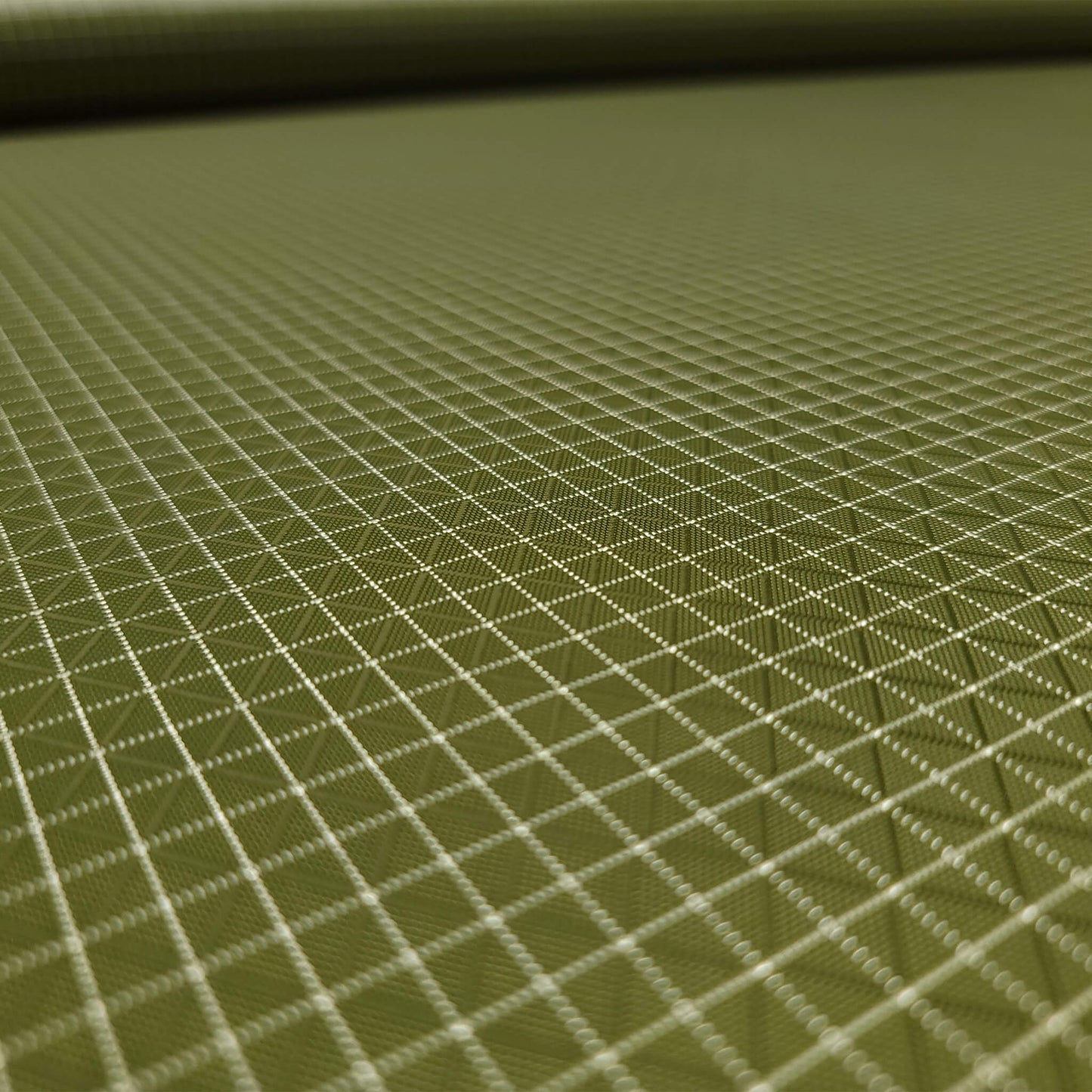 High-quality image showcasing my Olive Green 210D UHMWPE Gridstop Nylon fabric, emphasizing its lightweight, durable woven texture and unique waterproof properties. The image highlights the fabric's intricate UHMWPE fiber grid, its robust 210D denier thickness, and the dual protective coating – 1000mm PU on the back and DWR on the front. Ideal for visualizing the fabric's application in making resilient, weather-resistant outdoor gear like backpacks, fanny packs, and reinforcement areas.