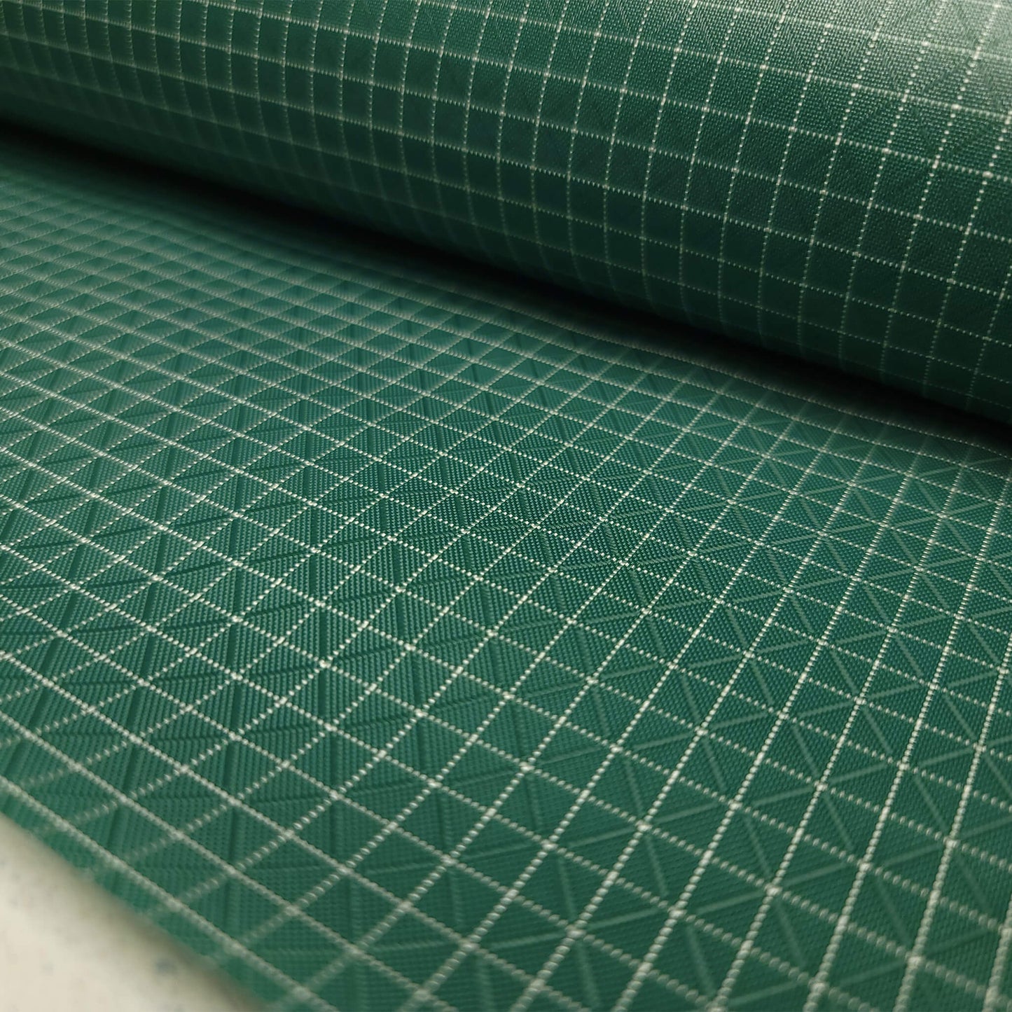 High-quality image showcasing my Pine Green 210D UHMWPE Gridstop Nylon fabric, emphasizing its lightweight, durable woven texture and unique waterproof properties. The image highlights the fabric's intricate UHMWPE fiber grid, its robust 210D denier thickness, and the dual protective coating – 1000mm PU on the back and DWR on the front. Ideal for visualizing the fabric's application in making resilient, weather-resistant outdoor gear like backpacks, fanny packs, and reinforcement areas.